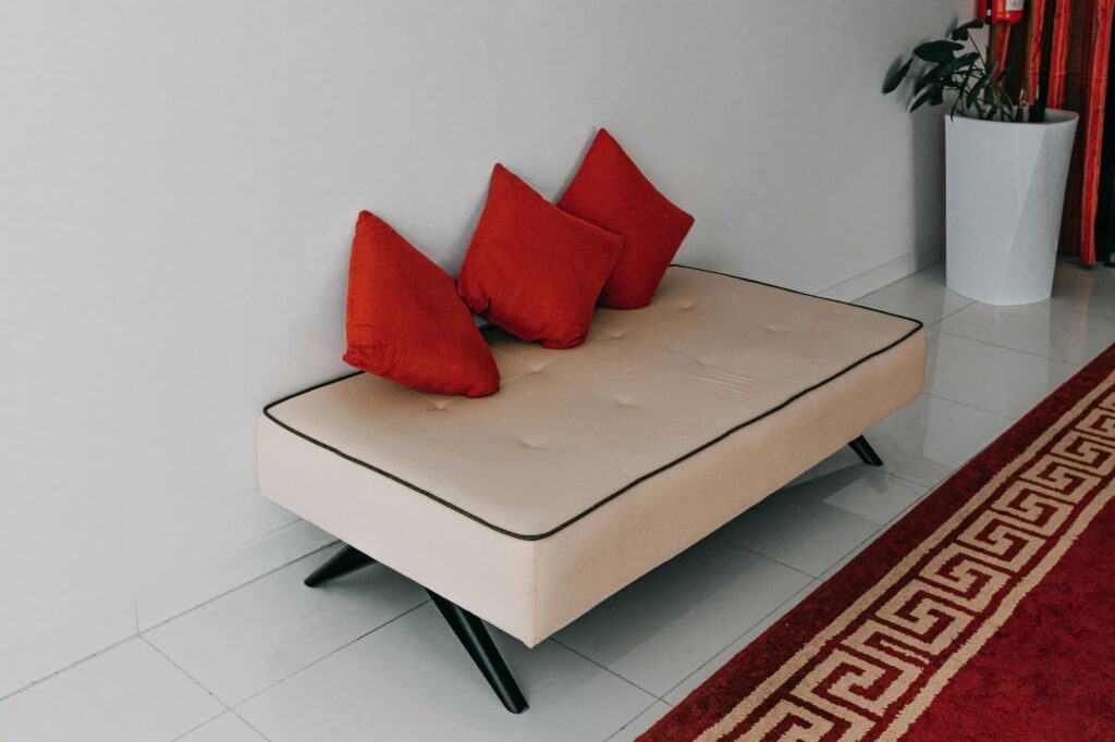 A cream-coloured sofa with three red pillows in the concept of a single-item move