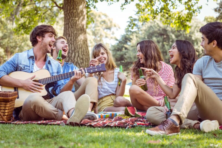 A group of happy friends picnicking in a public green space in the concept of 'best parks and green spaces in Balham'.