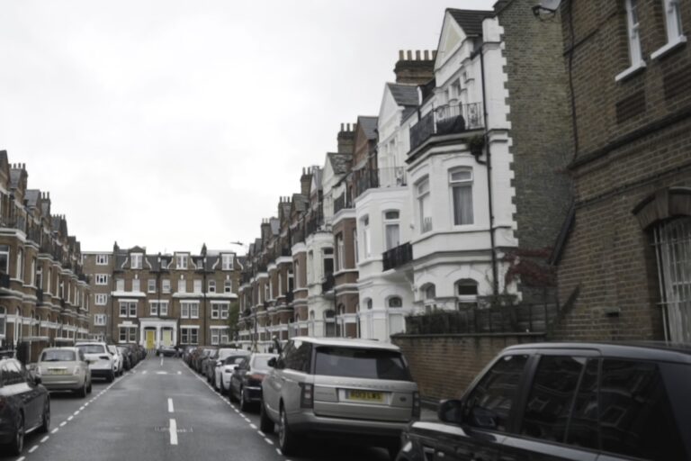 A narrow street with brick houses and parked cars in the concept of affordable housing options in Balham.